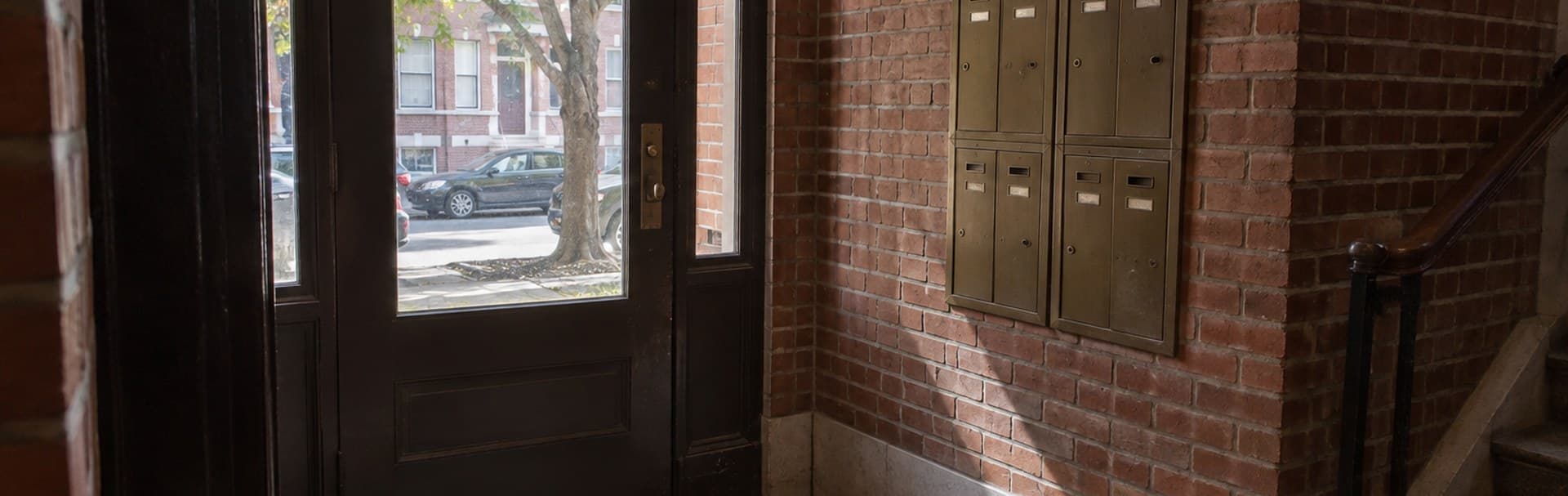 Brick apartment entry with a door and mailboxes before an entry-system project