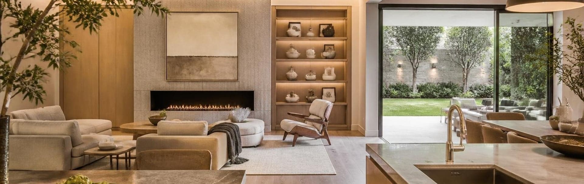 Open-plan living room and kitchen with layered lighting and a view to the patio