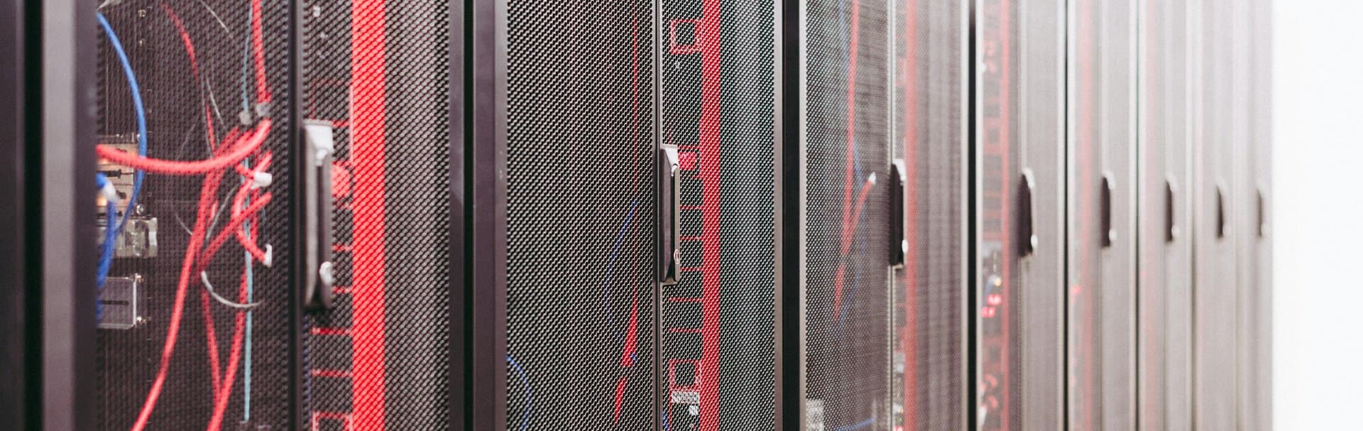 Rows of professional network server racks with red cables — representing the structured infrastructure behind a managed Wi-Fi 7 deployment