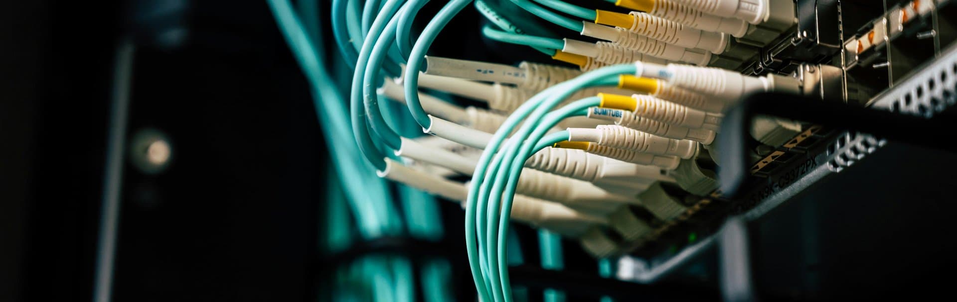Teal fiber optic cables neatly connected to a professional network rack switch — illustrating the clean, structured cabling behind a premium home network installation