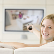 woman in living room watching television smiling